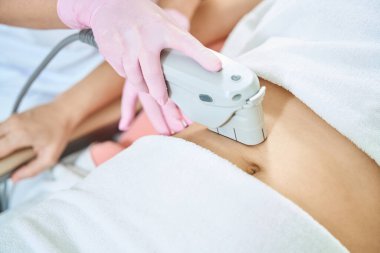 Kadın güzellik uzmanının, bulanık güzellik salonunda IPL fotorejuvenation cihazıyla lazer epilasyonu yaparken çekilmiş görüntüsü. Vücut bakımı kavramı