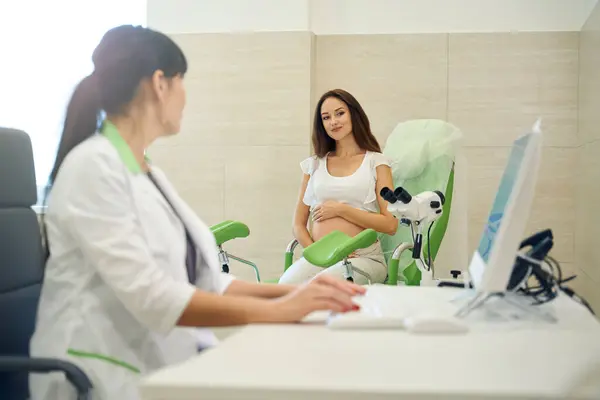 Ung Kaukasisk Gravid Kvinna Tittar Kvinnlig Gynekolog Skriva Datorn Undersökningen — Stockfoto