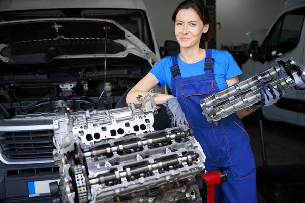 stock image Woman holds a part of a modern car in her hands, the master works in protective gloves and overalls