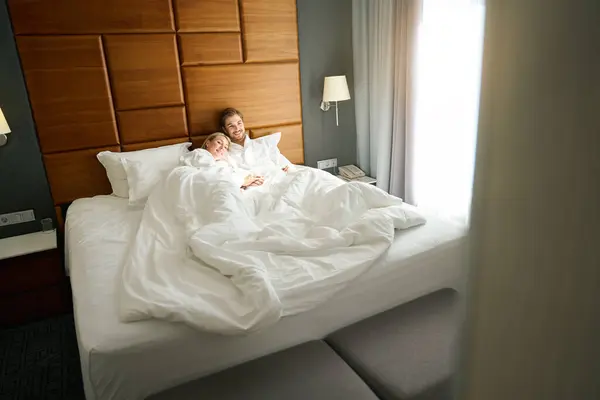 Woman Man Lie Hugging Large Bed Wearing Hotel Terry Robes — Stock Photo, Image