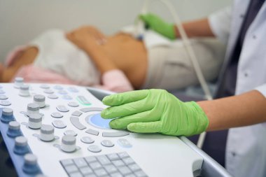 Klinikteki bulanık hamile kadına ultrason yapan kadın jinekoloğu kullanarak ultrason cihazlarının ön planına odaklan. Hamilelik testi kavramı