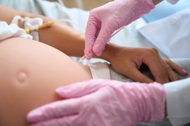 Kadın doğum kliniğinde hamile bir kadının karnına şırınga enjekte ederken çekilmiş görüntüler.