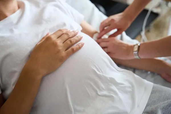 Selektiver Fokus Von Abgeschnittenem Schwangerschaftsbauch Während Eine Teilweise Verschwommene Krankenschwester — Stockfoto