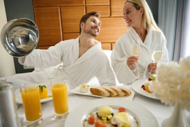 Çiftler büyük bir yatakta otururken şampanya içmekten hoşlanırlar.