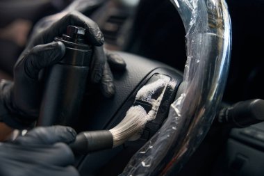 Koruyucu eldiven giyen bir uzman arabanın içinde temizlik için özel temizlik köpüğü kullanıyor.