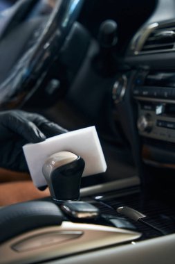 Adam araba parçalarını süngerle temizliyor, sürücü koltuğuna oturuyor.