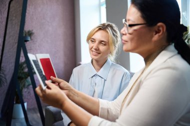 Kadınlar kumaşı renk tipine göre seçme sürecinde, kadınlar rahat bir kanepeye otururlar.