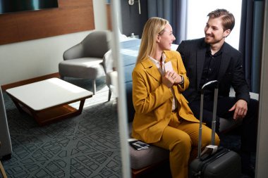 Mutlu yeni evliler otele vardılar. Seyahat kıyafetleri ve bavulları olan insanlar.