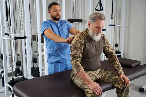 Arzt Untersucht Rücken Eines Mannes Militärkleidung Patient Sitzt Auf Massagetisch — Stockfoto