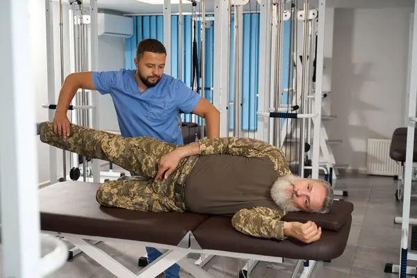 Patiënt Camouflage Kleding Ligt Een Massagetafel Een Ervaren Massagetherapeut Werkt — Stockfoto