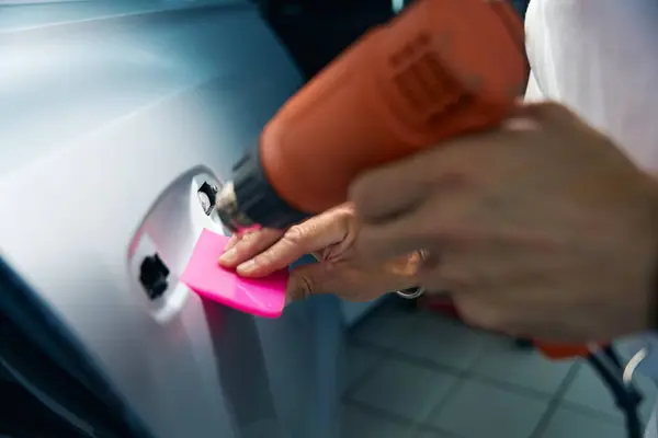 Industrial dryer in the hands of a repairman, he glues anti-gravel film on the car doors