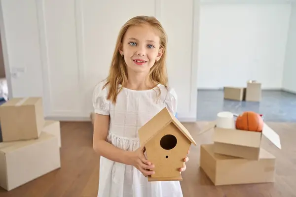 Uśmiechnięta Biała Dziewczynka Trzymająca Drewniany Domek Dla Ptaków Patrząca Kamerę — Zdjęcie stockowe