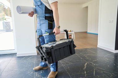 Tamir edilmeden önce modern konforlu konaklama evindeki taslak ve alet çantasıyla erkek işçi veya mühendisin kesilmiş görüntüsü.