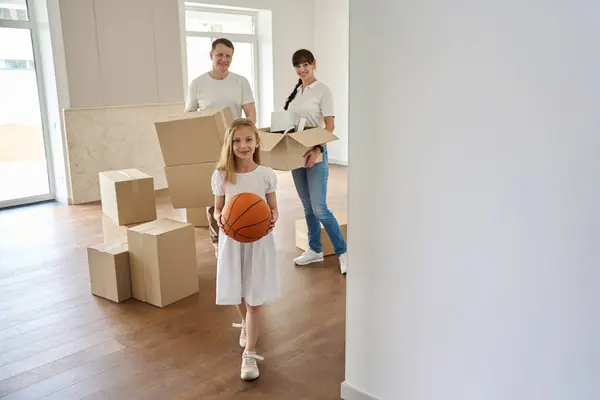 Parents and their daughter are moving to a new country house, people are moving boxes of things