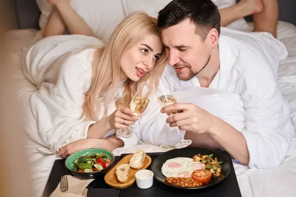 Šťastný Pár Snídaní Posteli Šampaňským Lidé Načechraných Županech — Stock fotografie