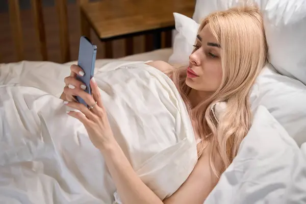 Charmante Blonde Repose Sur Des Oreillers Moelleux Avec Téléphone Portable — Photo