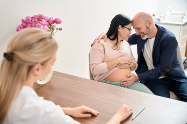 Yetişkin bir adam ve hamile karısı, anne karnında sağlıklı bir bebek sahibi olmaktan mutlu. Jinekoloji ve üreme kliniğinde hamileliği kontrol ediyorlar.