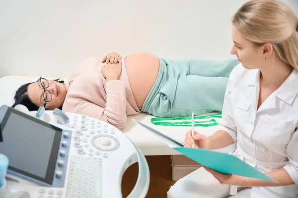 Attentive Woman Gynecologist Talking Pregnant Woman Filling Medical Records Fetus — Stock Photo, Image