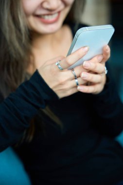 Bulanık, gülümseyen Asyalı bir kadın kullanarak akıllı telefonun ön planına odaklan. Modern serbest çalışma kavramı veya uzak çalışma