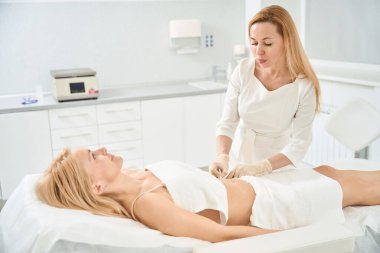 Estetik tıp kliniğinde estetik tıp kliniğinde karın gerdirmeye estetik cerrahiye alternatif olarak karın gerdirmeye, iplik çözme terapisine hazırlayan uzman bir terapist.