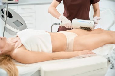 Kadın müşterinin üst bacak bölgesi üzerinde Endosphere terapisi uygulayan yetenekli bir phlebologist. Sıvı medyanın güçlü şekilde boşaltılması ve dokulardan lenf ve venöz kan alınması.