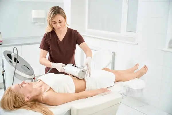 stock image Woman client lying on the medical couch while high-qualified dermatocosmetologist doing rejuvenation therapy that simultaneously smoothing, toning, improving microcirculation and shapes