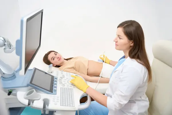 現代の診療所で若いヨーロッパ人女性の妊娠中の腹の超音波スキャンを行っている女性の白人婦人科医 妊娠と出産の概念について — ストック写真