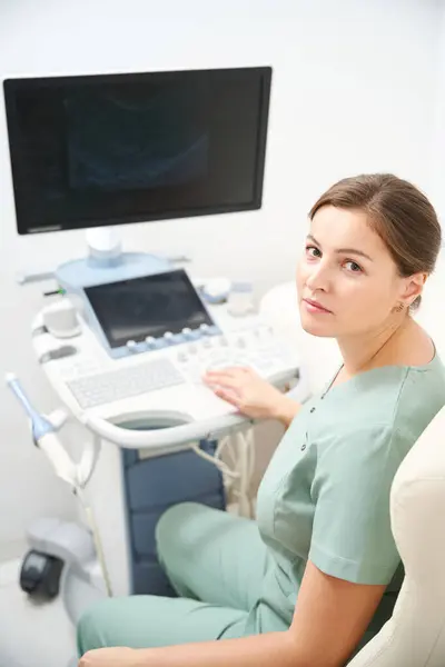 Klinikte Bulanık Ultrason Makinesi Üzerinde Çalışırken Kameraya Bakan Beyaz Kadın — Stok fotoğraf