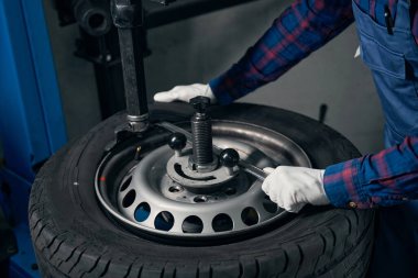 Koruyucu üniformalı ve eldivenli bir adam direksiyona yakın duruyor ve durumu kontrol ediyor.