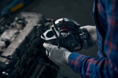 Koruyucu eldivenli bir erkek, araç hizmet merkezinde motor gücünü arttıran bir cihaz gösteriyor.