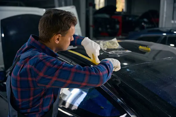 Man holds tape and seals parts on car. Surface preparation before painting automobile detail