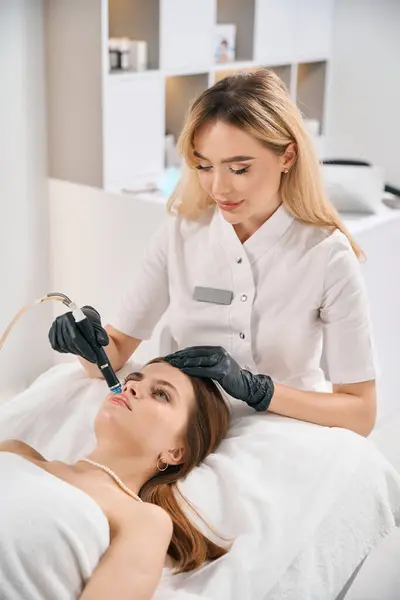 欧洲女性美容师在模糊的美容院为年轻的高加索女人做面部皮肤水疗 面部皮肤护理 整容及更新的概念 — 图库照片