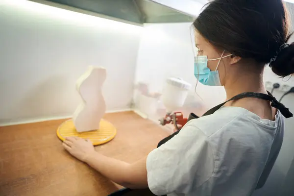 研修会でプロダクトを処理している間スプレーヤーが付いている陶磁器の部分を描く女性 — ストック写真