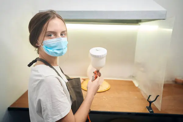 クリエイティブスタジオでエアブラシ粘土製品にスプレーを保持する女性ポッター — ストック写真