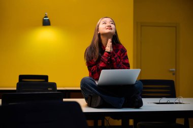 Endişeli, dua eden Asyalı genç bir bilgisayar çalışanı çalışma masasında dizüstü bilgisayarını kullanırken Hope 'a sorar. Modern serbest çalışma kavramı veya uzak çalışma
