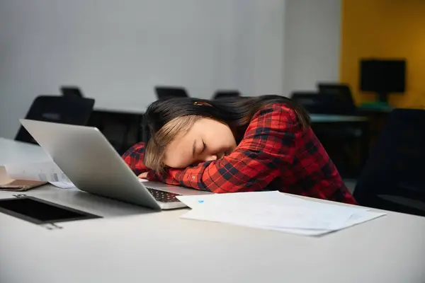 年轻疲惫的亚洲女性It员工睡在同事办公室的工作台上 现代自由职业或远程工作的概念 — 图库照片