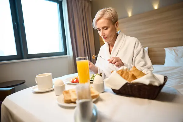 Dorosła Biała Kobieta Szlafroku Jedząca Śniadanie Łóżku Przy Stole Pokoju — Zdjęcie stockowe