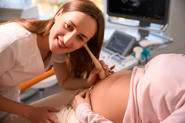 Concentrated Smiling Female Gynecologist Listening Belly Unrecognizable Pregnant Woman — Stock Photo, Image