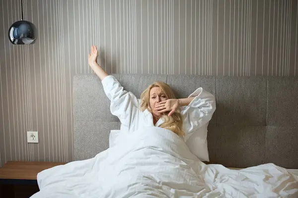 Sleepy Lady Terry White Bathrobe Seated Bed Wrapped Duvet Yawning — Stock Photo, Image