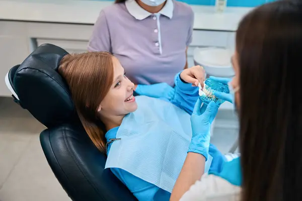 Žena Zubařka Demonstruje Model Zubního Kazu Dívčí Pacientce Zubní Asistentkou — Stock fotografie