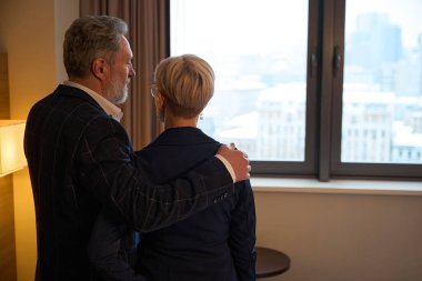 İş adamlarının gündüz vakti otel odasında sarılıp iş kadınlarına bakmaları. İş gezisi, tatil ve seyahat kavramı. Takım çalışması fikri