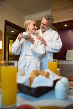 Gülümseyen beyaz adamın mutlu karısına sarıldığı, fincandan çay ya da kahve içtiği ve sabahları otel odasında birbirlerine baktıkları son manzara. Dinlenme, tatil ve seyahat kavramı. İlişki