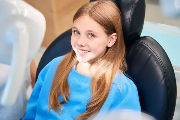 Cute girl at a reception in a dental clinic, she is sitting in a dental chair