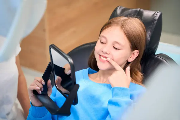 子供は鏡に白い歯を認め 彼女は歯医者オフィスにいる — ストック写真