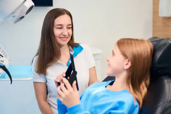 Flicka Tandläkarmottagning Tittar Sina Tänder Spegeln Bredvid Kvinnlig Tandläkare — Stockfoto