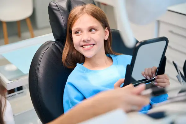 少女は鏡に白い歯を認め 彼女は歯科医のオフィスにいる — ストック写真