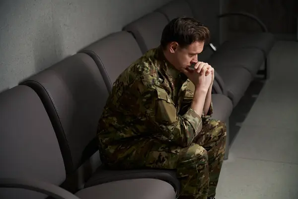 Soldado Abatido Uniforme Camuflaje Apoyando Barbilla Con Pulgares Sentados Sofá —  Fotos de Stock