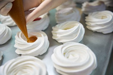 Merengue yuvasını taze elma püresiyle doldurmak için pasta torbası kullanan nitelikli bir kadın. Lezzetli mini Pavlova tatlısı hazırlamak, özel fırın.