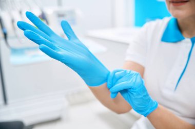 Yetenekli bir diş hekimi koruyucu lastik eldiven takıyor, sorunlu ve sürekli diş ağrısı olan bir hastayı tedavi ediyor, gülümseme makyajı yapıyor.