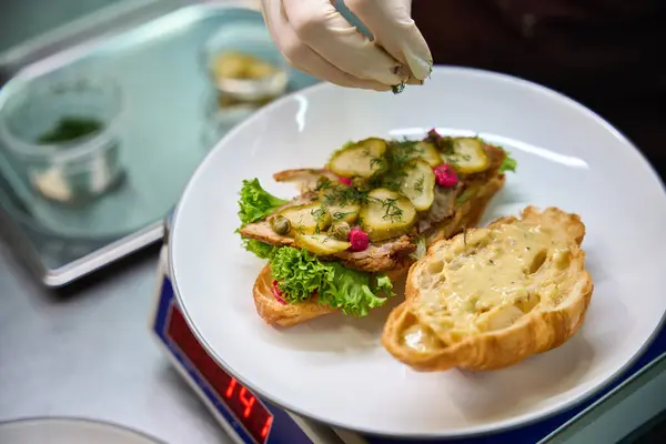 Nærbilde Kokk Dekorere Salat Skiver Svinekjøtt Sandwich Med Skiver Syltet stockbilde